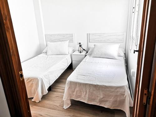 2 Betten in einem Zimmer mit weißen Wänden und Holzböden in der Unterkunft Apartamento a 1 MINUTO de la playa en GARRUCHA in Garrucha