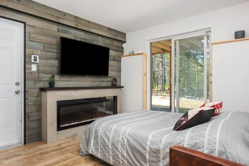 a bedroom with a fireplace and a tv on a wall at Chalet Natür Lakefront - Hot Tub - Fireplace - Ski - Waterfront - Private big land - Pedal Boat in Saint-Alphonse-Rodriguez