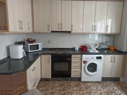 a kitchen with a stove and a washing machine at Las 4 columnas (MFA) in Muxia