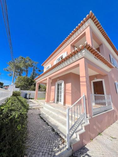 uma casa rosa com uma escada em frente em casa de praia em Charneca