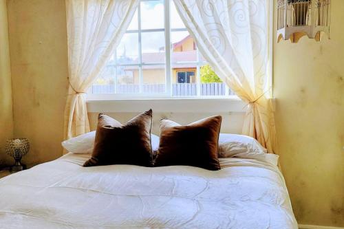 a bed with two pillows in front of a window at Surprisingly Styish Stays in Hoquiam