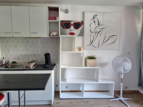 une cuisine avec des armoires blanches et un évier dans l'établissement Idéal Vacances petit budget, à La Grande Motte