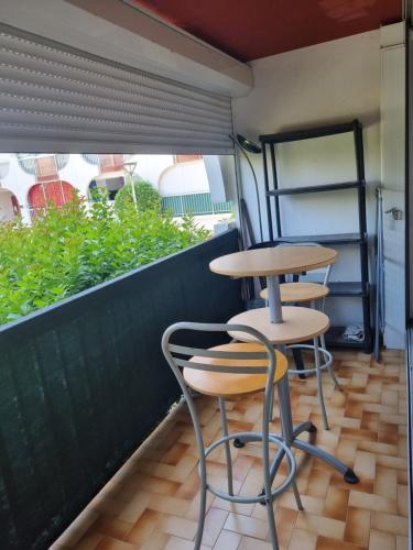 deux tables et deux tabourets assis sur une terrasse dans l'établissement Idéal Vacances petit budget, à La Grande Motte