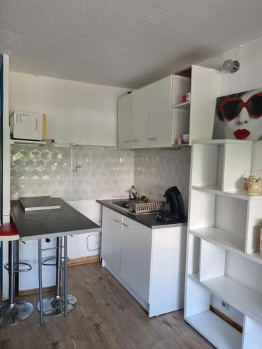 una cocina con armarios blancos y una mesa con gafas de sol en la pared en Idéal Vacances petit budget, en La Grande-Motte