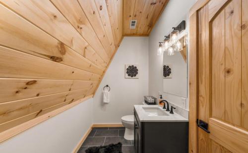 a bathroom with wooden walls and a toilet and a sink at Cabin Coco - June sale dates! Luxe A Frame with projector screen, arcade and swim spa in Sevierville