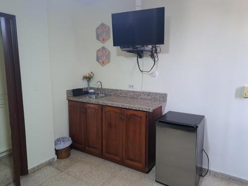 baño con lavabo y TV en la pared en D9 Casa de Huespedes, en Santo Domingo