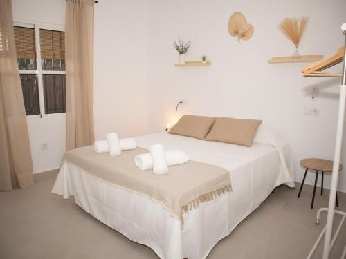 a white bedroom with a bed with towels on it at Villa Alegría in Chiclana de la Frontera