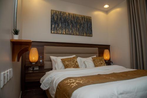 a bedroom with a large bed with two lamps at صالة وغرفتين نوم دخـول ذاتي in Al Kharj