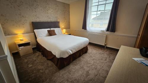 ein Hotelzimmer mit einem Bett und einem Fenster in der Unterkunft NELSON Hotel in Great Yarmouth