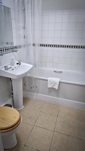 a bathroom with a toilet and a sink and a tub at NELSON Hotel in Great Yarmouth