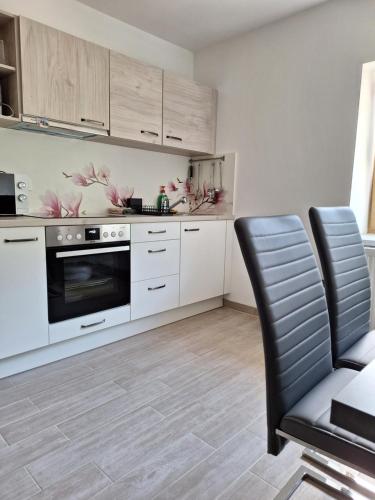 uma cozinha com armários brancos e uma cadeira preta em ALPSKA ROŽA em Kranjska Gora