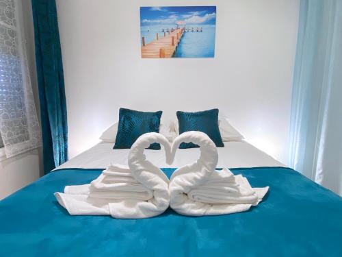 two white swans making a heart shape on a bed at Casaminnie - Appartement à 8 min de Disneyland Paris in Bussy-Saint-Georges
