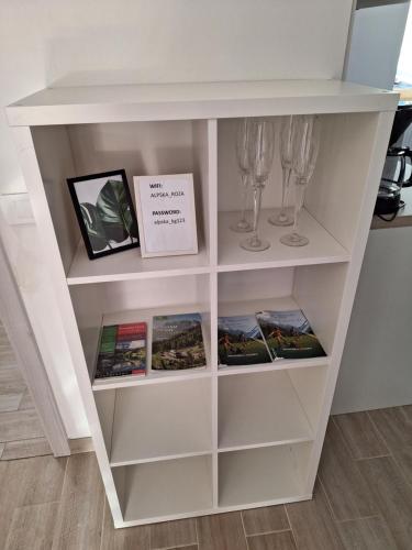 a white book shelf with wine glasses and books at ALPSKA ROŽA in Kranjska Gora