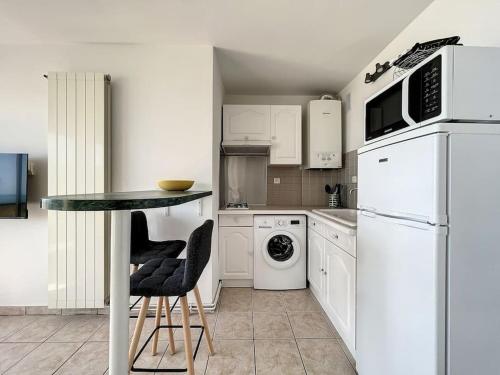 une cuisine avec des appareils blancs et une table avec des chaises dans l'établissement Studio 4 couchages face mer Noumarie, à Canet