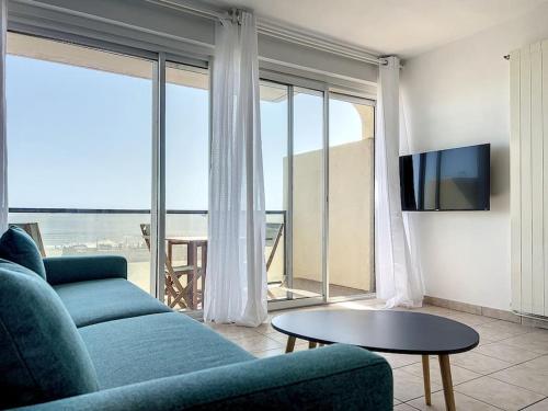 un salon avec un canapé bleu et une télévision dans l'établissement Studio 4 couchages face mer Noumarie, à Canet