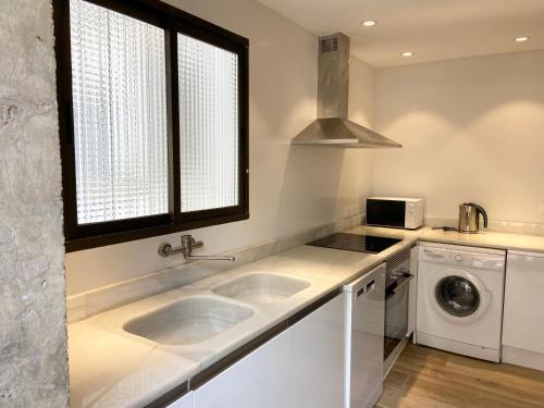 a white kitchen with two sinks and a window at Apartamento artístico en el centro de Segorbe in Segorbe