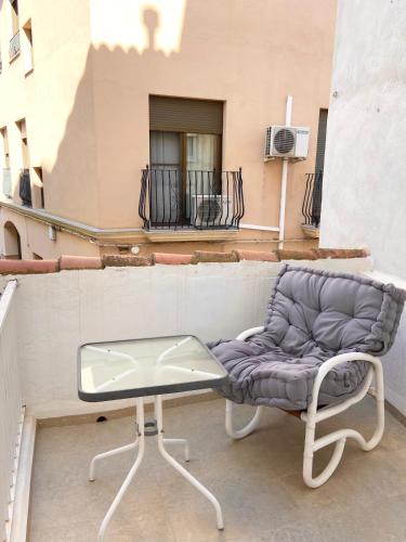 a chair and a glass table on a balcony at Apartamento artístico en el centro de Segorbe in Segorbe