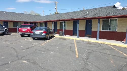 2 voitures garées sur un parking en face d'un immeuble dans l'établissement Travelers Motel, à Elko