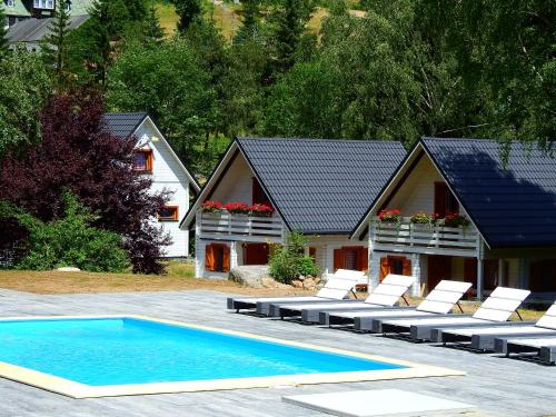 a swimming pool with lounge chairs and a house at Dom Stary Młyn nad strumieniem z dostępem do sauny, gorącej beczki, basenem in Szklarska Poręba