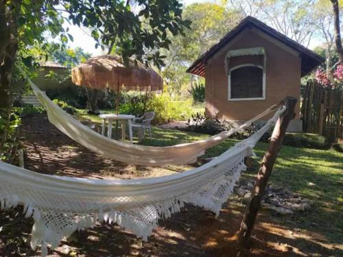 a hammock in a yard with a hut at Chalés SFX in São Francisco Xavier