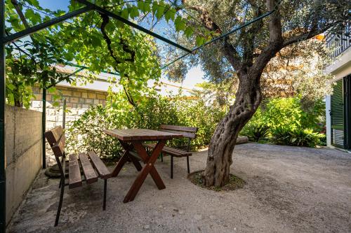 une table de pique-nique et un banc à côté d'un arbre dans l'établissement Petrovac Holiday Apartments 2, à Petrovac na Moru