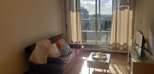 un soggiorno con divano, tavolo e ampia finestra di Frente a Terminal Tres Cruces. a Montevideo