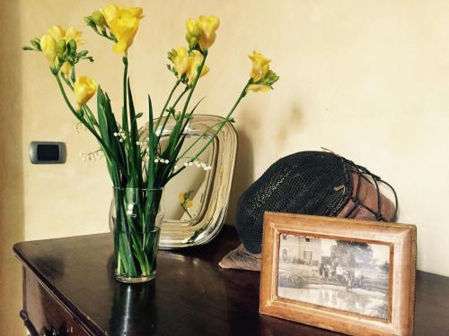 a vase with yellow flowers on a table next to a picture at B&b Villa Partitore in Quartazzola