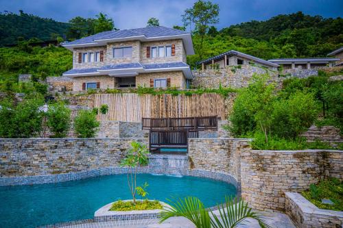 a house with a swimming pool in front of a stone wall at Dorje's Resort and Spa in Pokhara