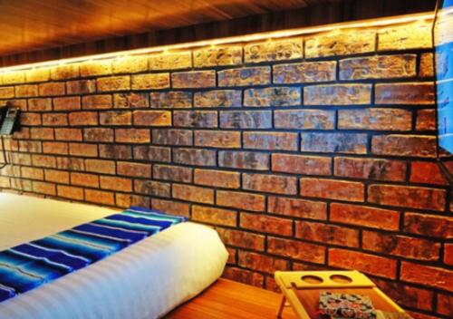 a brick wall next to a bed in a room at Cadillac Hotel Boutique in Mexico City