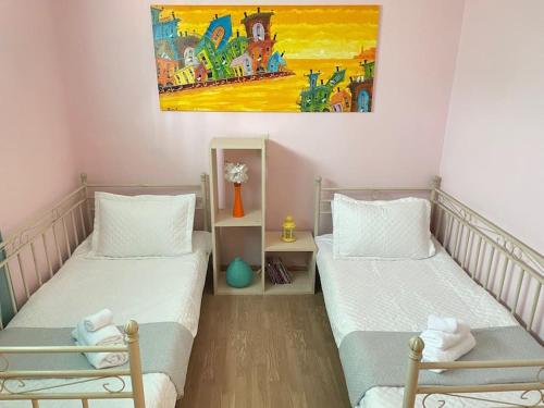 a room with two beds and a painting on the wall at Sweet Makri Suite in Nea Makri
