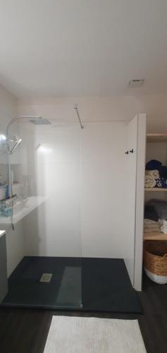 Cette chambre est dotée d'un mur blanc et d'une porte en verre. dans l'établissement Maison au calme proche de l'océan et du golf, à Talmont-Saint-Hilaire