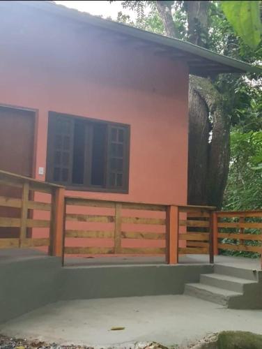 a house with a wooden fence and a tree at Pousada Pé da Mata Maresias in Maresias