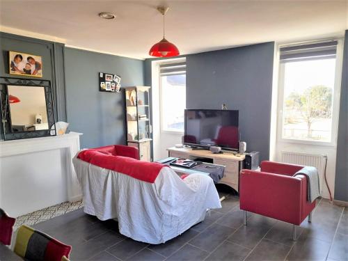 Gîte Le Mirador في Vicq-dʼAuribat: غرفة معيشة فيها كرسيين احمر وتلفزيون