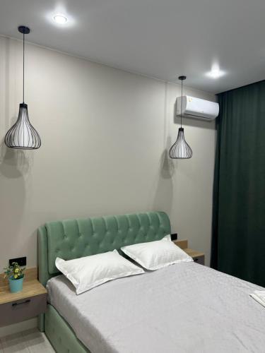 a bedroom with a green bed with two lights at Люксовая Квартира in Aktobe