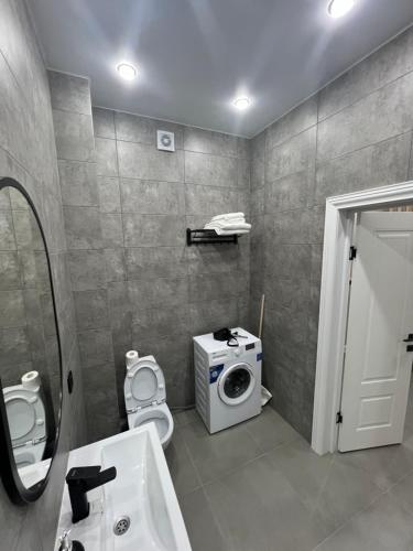 a bathroom with a toilet and a washing machine at Люксовая Квартира in Aktobe