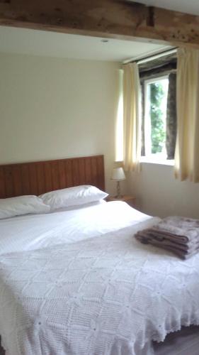 a bedroom with a large white bed with a window at Millstone cottage in Oldham