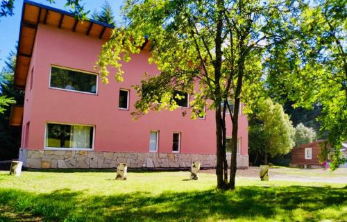 ein rosa Haus mit einem Baum davor in der Unterkunft Casita Silvestre y Casa Rosa in Villa La Angostura