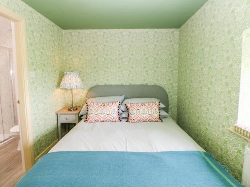 ein Schlafzimmer mit einem Bett mit grüner Tapete in der Unterkunft The Granary in Morpeth