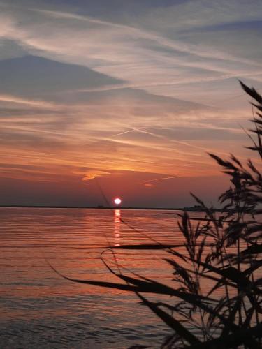 a sunset over a body of water with a boat at Studio Flevo Batavia in Lelystad