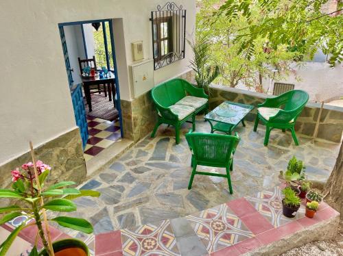 a patio with green chairs and a table and chairs at Casa Amigos Sorvilan- La Palmera in Sorvilán