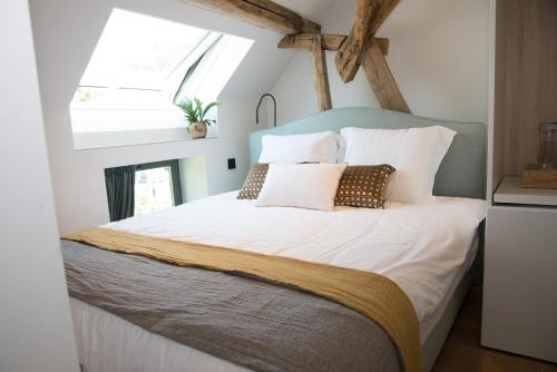 een slaapkamer met een groot bed met witte lakens en kussens bij B&B Kraneveld in Haacht