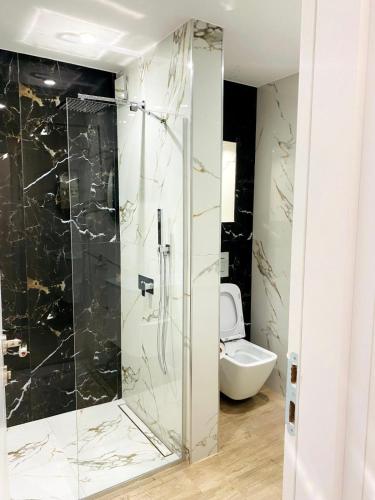 a bathroom with a glass shower with a toilet at DiP HOME APARTMENTS in Pomorie