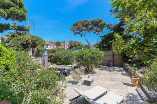 un patio avec des tables et des chaises dans un jardin dans l'établissement Superb 3BR with AC Sea view PARKING and Garden - BENAKEY, à Cannes