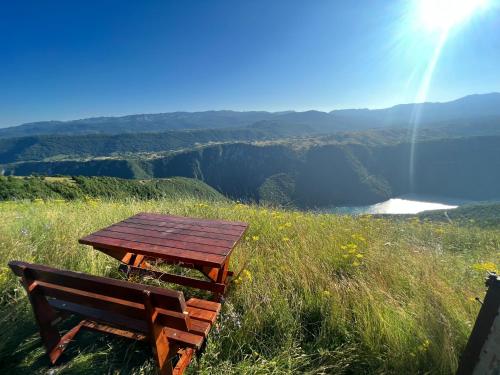 a wooden table and bench sitting on a grassy hill at Guest House Highland in Pluzine