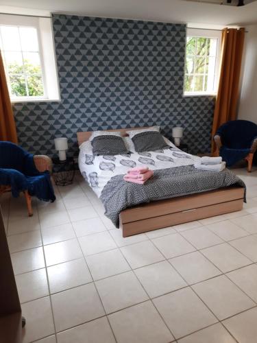 a bedroom with a bed and two windows at La hervuerie in La Haye-du-Puits