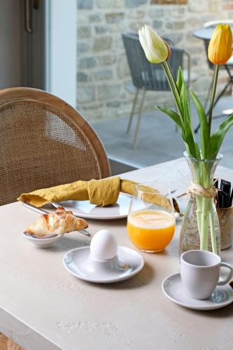 a table with a plate of food and a vase of orange juice at Tenuta Bussia - Wine Relais & Spa in Monforte dʼAlba