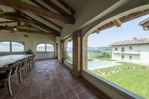 una sala da pranzo con ampie finestre, tavolo e sedie di Tenuta Bussia - Wine Relais & Spa a Monforte dʼAlba