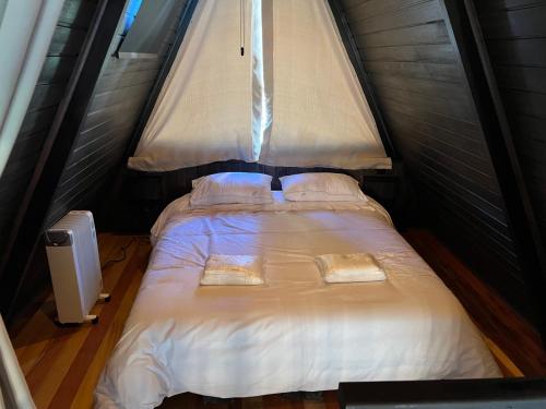 een bed in een kleine kamer met een raam bij Chalé Villa Nature in Campos do Jordão