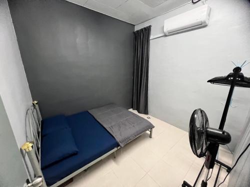 a small bedroom with a blue bed and a fan at 2 Bedroom house with Coway, all room air-cond, WIFI, Nettflix in Kampung Gurun