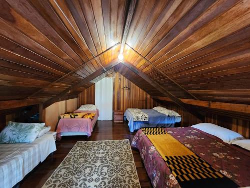 three beds in a room with a wooden ceiling at A casa Girassol in Campos do Jordão